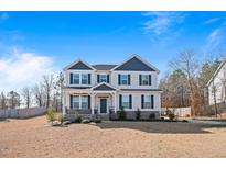 Charming two-story home featuring a well-maintained lawn and inviting front porch with stone accents and dark shutters at 594 Executive Dr, Lillington, NC 27546