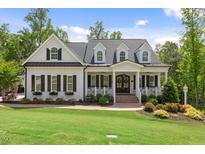 Charming two-story traditional home featuring a manicured lawn, mature trees, and a welcoming front porch at 175 Stonecrest Way, Pittsboro, NC 27312