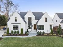 Stunning modern home featuring a manicured lawn, gray stone walkway, white brick exterior, and a black shingle roof at 4329 Lambeth Dr, Raleigh, NC 27609