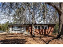 Charming single-story home with a brick facade and well-maintained front yard surrounded by mature trees at 5136 Melbourne Rd, Raleigh, NC 27606