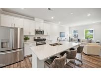 Bright, open kitchen with stainless steel appliances, white cabinets, and a large center island with bar seating at 683 Mirkwood, Apex, NC 27523
