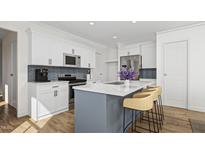 Bright kitchen with white cabinets, stainless steel appliances, light countertops, and a blue island at 923 Selby Ave, Durham, NC 27713