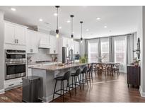 Bright kitchen boasts white cabinets, stainless steel appliances, island seating and an adjacent dining area at 1014 Falling Rock Pl, Durham, NC 27703