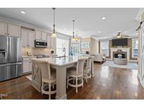 Open kitchen featuring a large island with seating, stainless steel appliances, and hardwood floors at 1117 Golden Star Way, Wake Forest, NC 27587