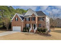 Charming two-story red brick home with a manicured lawn and a two-car garage at 1122 Virginia Water Dr, Rolesville, NC 27571