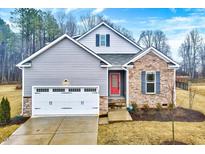 Charming home featuring a stone and siding exterior, attached two-car garage, well-maintained landscaping, and inviting coral colored front door at 186 Madden Rose Loop, Garner, NC 27529