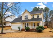 Charming yellow two-story home with a well-manicured front yard and covered porch at 2011 Henniker St. St, Apex, NC 27523