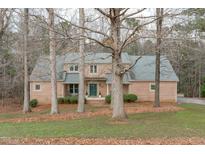 Charming brick home with a lush front lawn and mature trees providing shade and character at 5512 Spring Bluffs Ln, Raleigh, NC 27606