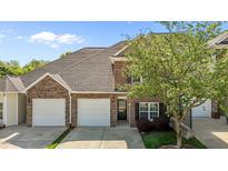 Inviting brick townhouse featuring a two-car garage, manicured lawn and easy access to the front door at 638 Village Lake Dr, Mebane, NC 27302