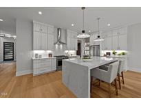 Modern white kitchen featuring a large center island, stainless steel appliances, and hardwood floors at 809 Tower St, Raleigh, NC 27607