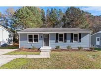 Charming single-story home featuring light blue siding, a gray front door, and neatly landscaped front yard at 1211 Freeman Dr, Sanford, NC 27330