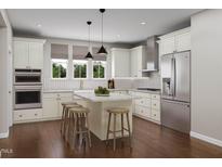 Bright kitchen features white cabinets, stainless steel appliances, large island with seating, and views of the outdoors at 2019 Trident Maple Ln, Chapel Hill, NC 27517