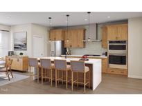Bright kitchen features wood cabinetry, stainless steel appliances, and large center island with bar stool seating at 2021 Trident Maple Ln, Chapel Hill, NC 27517