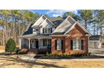 Inviting two-story home featuring a charming front porch and manicured landscaping at 1328 Wakefield Farm Rd, Zebulon, NC 27597