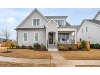 Charming home featuring a covered porch, white brick accents, and manicured landscaping at 1733 Deacon Falls Way, Wendell, NC 27591