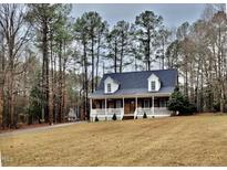 Charming brick home boasts a welcoming front porch and a well-maintained yard surrounded by mature trees at 266 Sagamore Dr, Louisburg, NC 27549