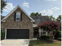 Charming stone-front home with a dark garage door and a beautiful flowering tree in the front yard at 3108 Fortress Gate Dr, Raleigh, NC 27614