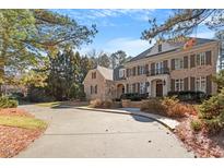 View of a beautiful brick house with black shutters and a large driveway surrounded by trees at 3605 Camp Mangum Wynd, Raleigh, NC 27612