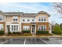 Charming townhome featuring stone accents, a landscaped front, and convenient parking at 5117 Singing Wind Dr, Raleigh, NC 27612