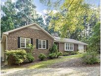 Charming brick home featuring black shutters and mature trees for ample shade at 6025 Spring Valley Dr, Raleigh, NC 27616