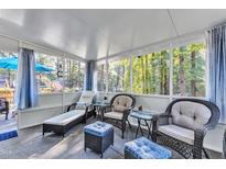 Inviting sunroom with wicker furniture, chaise lounge, and views of the surrounding trees at 104 Piquot Drive, Louisburg, NC 27549