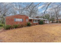 Charming brick home featuring a well-maintained lawn, complemented by mature trees and blue shutters at 2005 Sutphin Dr, Sanford, NC 27330