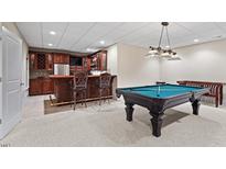 Finished basement featuring a bar with seating and a pool table for entertainment at 216 Copper Beech Ct, Chapel Hill, NC 27517