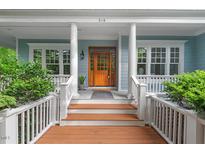 Inviting front entrance with a wooden door, white columns, and lush greenery enhancing its curb appeal at 216 Copper Beech Ct, Chapel Hill, NC 27517