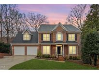 Charming brick home with a two-car garage, manicured lawn, and beautiful landscaping at sunset at 407 Crickentree Dr, Cary, NC 27518