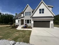 Charming two-story home featuring light gray brick, dark garage door and beautifully landscaped front yard at 5705 Flowery Meadow Ct, Wake Forest, NC 27587