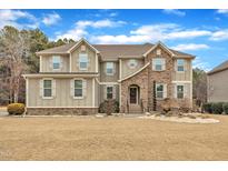 Stunning two-story home boasts stone accents, complemented by a lush front yard, and a welcoming entrance at 6509 Sunset Manor Dr, Wake Forest, NC 27587
