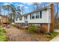 Charming two-story home featuring blue shutters and a brick driveway surrounded by trees and landscaping at 1105 Manchester Dr, Cary, NC 27511