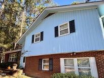 Two-story home featuring light blue siding, brick base, and black window shutters at 1200 W Main St, Carrboro, NC 27510