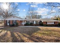 Charming brick home with a well-manicured lawn and mature trees on a sunny day at 1314 Briarcliff Rd, Burlington, NC 27215
