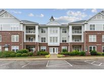 Beautiful condo building with brick and gray siding, balconies, landscaping, and ample parking at 232 Eyam Hall Ln, Apex, NC 27502