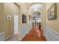 Inviting hallway with hardwood floors, white wainscoting, archway and views to the living area at 2815 Mebane Ln, Durham, NC 27703