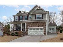 Charming two-story home with a stone facade, inviting porch, and a three-car garage, offering both elegance and practicality at 464 Granite Saddle Dr, Rolesville, NC 27571