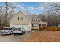 Charming two-story home with attached two car garage, front porch and mature trees at 589 Vinson Rd, Clayton, NC 27527
