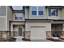 Inviting townhome with a well-manicured lawn, stone accents, and attached one car garage at 7727 Weathered Oak Way, Raleigh, NC 27616