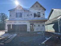 New construction home featuring an attached two-car garage and covered entry, with a bright sunlit view at 88 Windchime Ct, Fuquay Varina, NC 27526