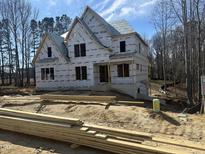 New home exterior featuring the front facade and construction materials in a partially wooded lot at 211 Meadow Walk Dr, Fuquay Varina, NC 27526