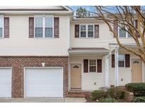 Two-story townhome with attached garage, brick facade, and light yellow vinyl siding at 4618 Pooh Corner Dr, Raleigh, NC 27616