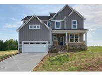 Charming two-story home featuring a stone foundation, inviting front porch, and a convenient two-car garage at 4881 Grosbeak Ct, Mebane, NC 27302