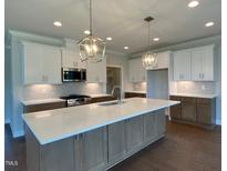Bright kitchen features a large island, modern stainless appliances, and stylish pendant lighting at 4881 Grosbeak Ct, Mebane, NC 27302