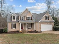 Charming two-story home with a front porch, manicured lawn, and attached two-car garage at 66 Windsong Dr, Pittsboro, NC 27312
