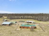 Sprawling property featuring a brick home, multiple outbuildings, fenced acreage, and mature trees at 9550 Silk Hope Liberty Rd, Siler City, NC 27344