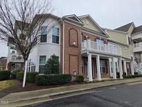Beautiful townhouse with a red brick facade, white columns, and an open balcony at 10420 Sablewood Drive Dr # 102, Raleigh, NC 27617