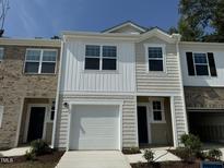 A charming townhome featuring a one-car garage, brick and vinyl siding, and a well-manicured front yard at 2117 Trailside Dr, Durham, NC 27704