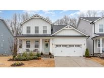 Charming two-story home with white siding, a covered porch, and a two-car garage, creating a welcoming curb appeal at 349 Shadow Falls Dr, Wendell, NC 27591