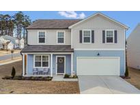 Charming two-story home with a well-manicured lawn, attached garage, and inviting front porch with seating at 3512 Dragonfly River Ct, Raleigh, NC 27604